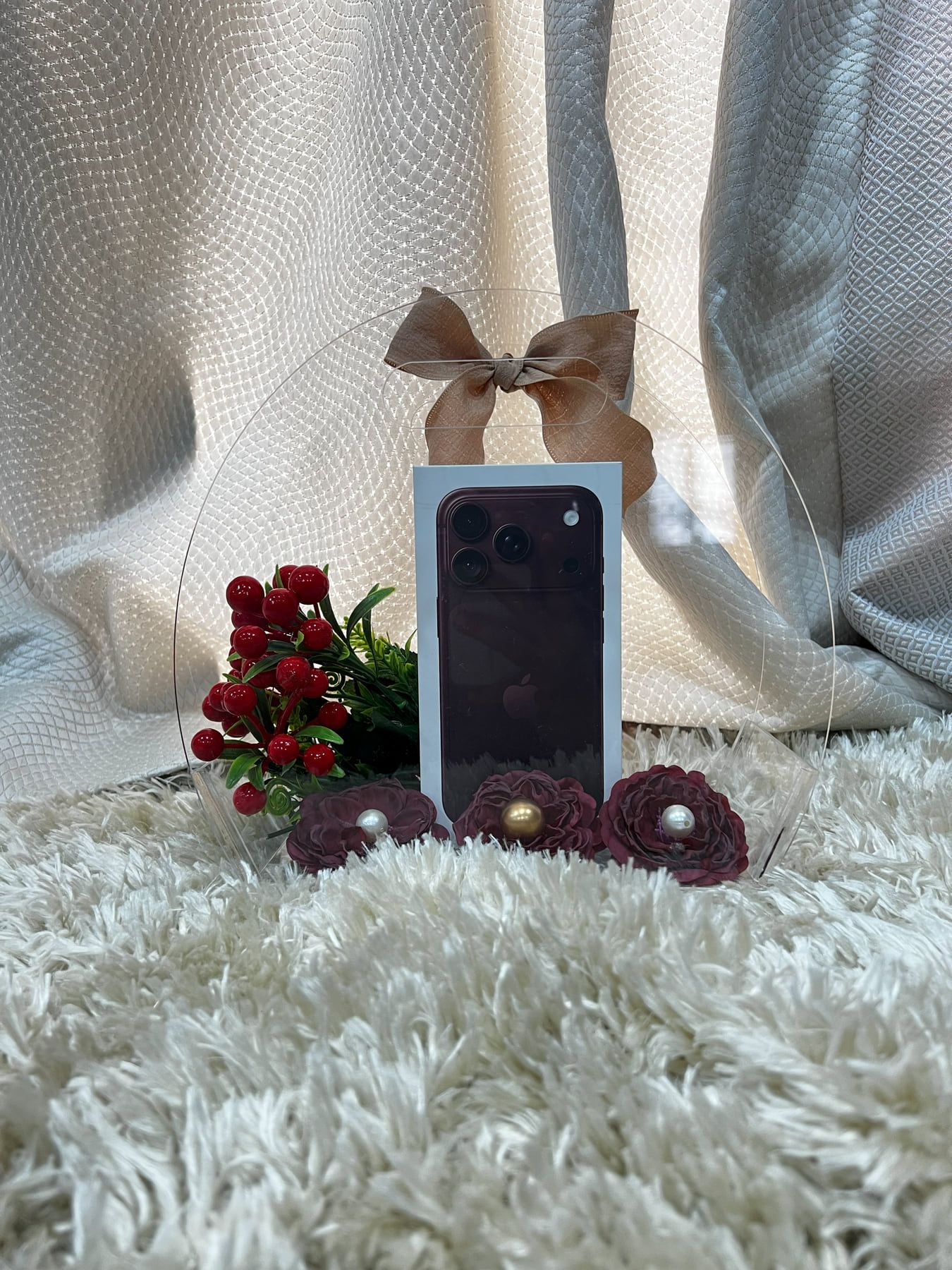 New phone box presented under a clear dome with a brown satin bow and dark red roses